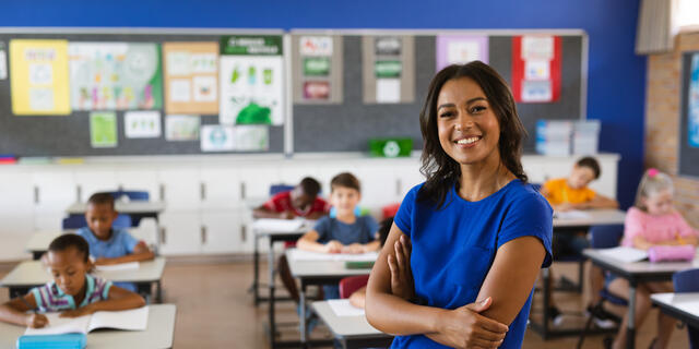 A female teacher standing in a classroom of students.