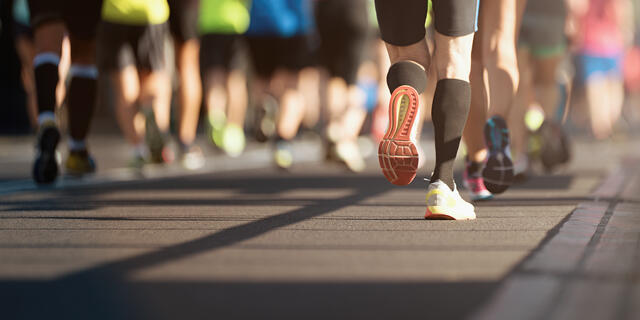 The legs and sneakers of marathon runners in the middle of a race.