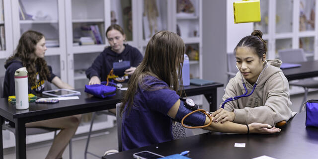 Students measure each other's blood pressure in a health sciences lab.