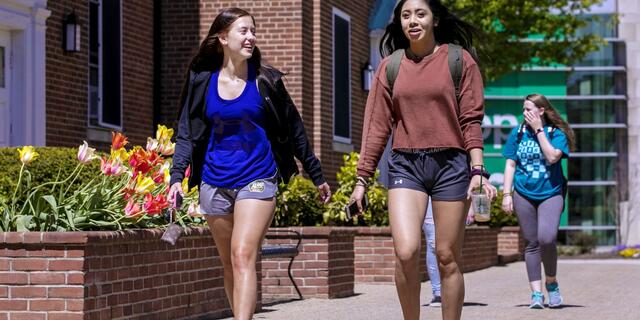 two female students walking on college campus in spring